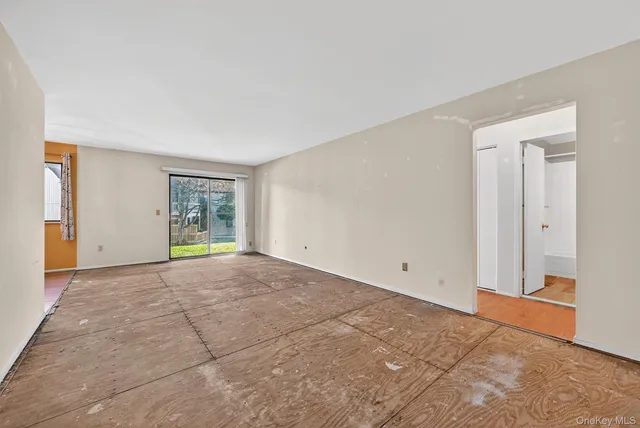 a view of an empty room with window and wooden floor
