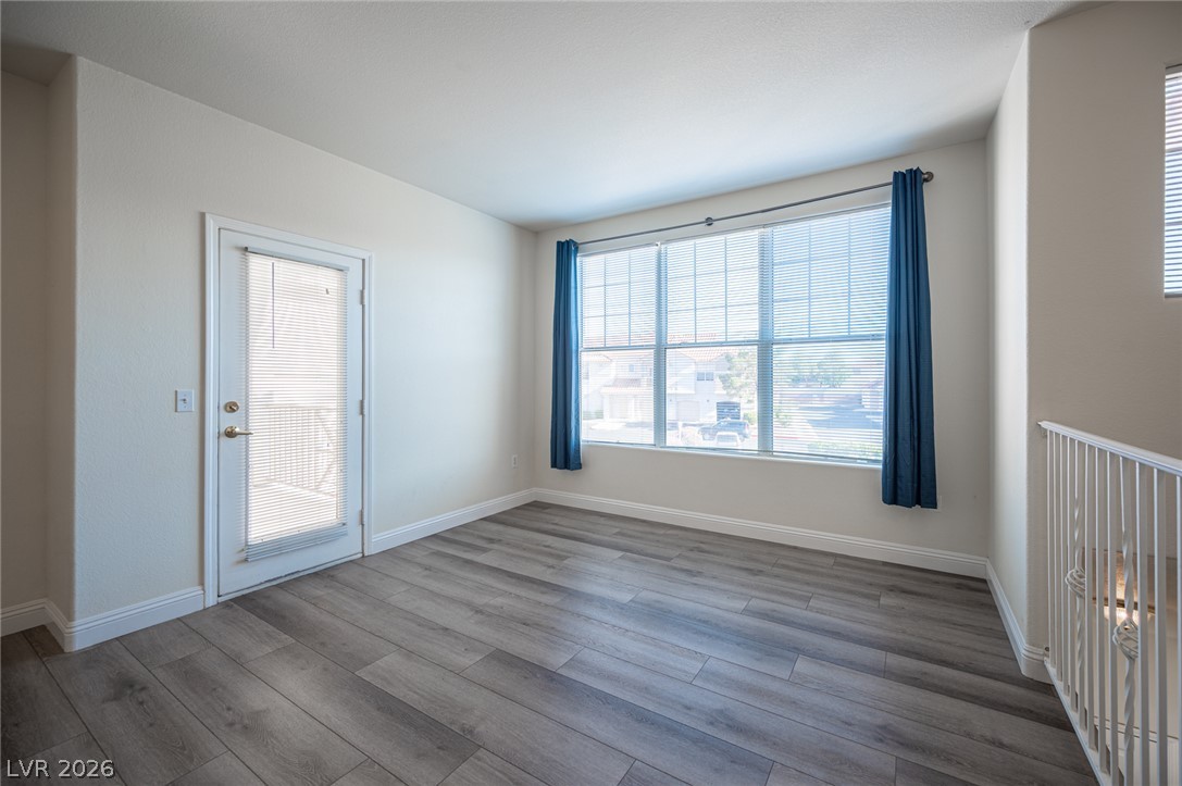 8555 West Russell Road, Unit 2062 Las Vegas, NV 89113 - Photo 9 of 35 Natural light floods this versatile space, featuring durable wood-look flooring and a private balcony access.