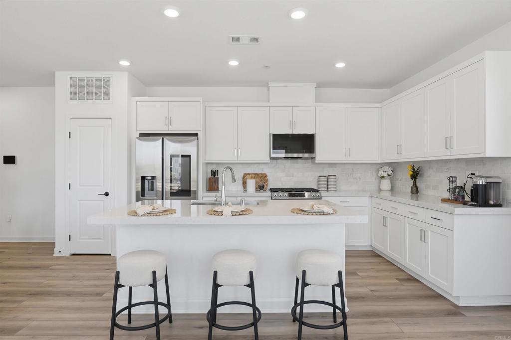 2402 Cascalote Loop San Diego, CA 92154 - Photo 7 of 35 a kitchen with white cabinets stainless steel appliances and sink