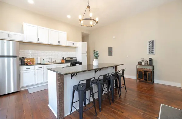 a kitchen with stainless steel appliances granite countertop a sink a stove and chairs
