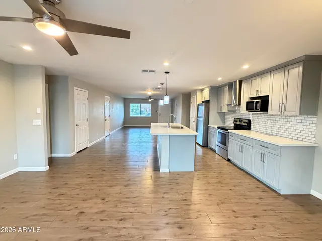 a large kitchen with kitchen island a sink wooden floor and stainless steel appliances