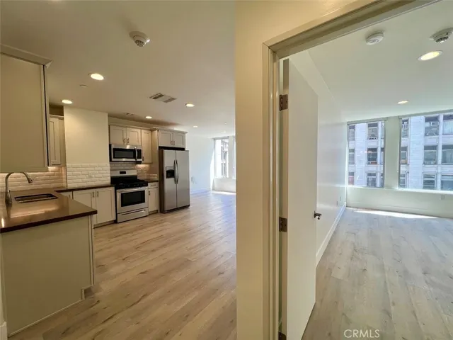 a view of kitchen with stainless steel appliances kitchen island wooden floor and living room