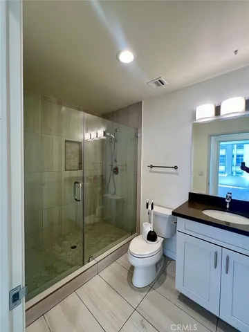 a spacious bathroom with a granite countertop sink a toilet a mirror and a glass door shower
