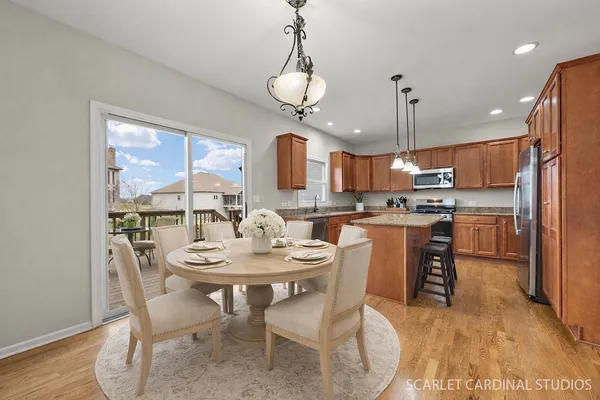 a kitchen with stainless steel appliances granite countertop a stove top oven a refrigerator a sink and a dining table with wooden floor