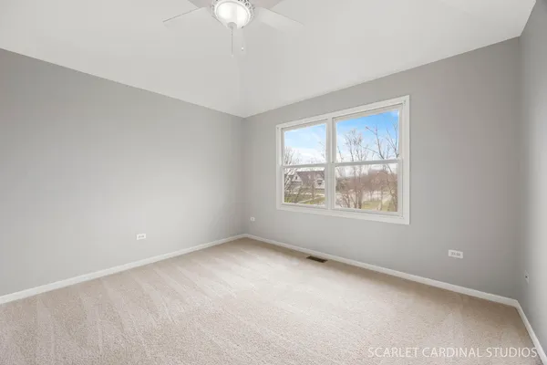 an empty room with windows and fan
