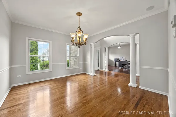 a view of a livingroom with a chandelier wooden floor and a table