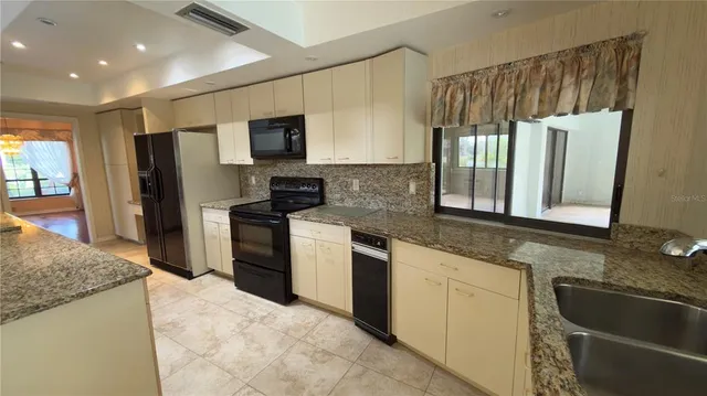a kitchen with granite countertop a sink stove and refrigerator