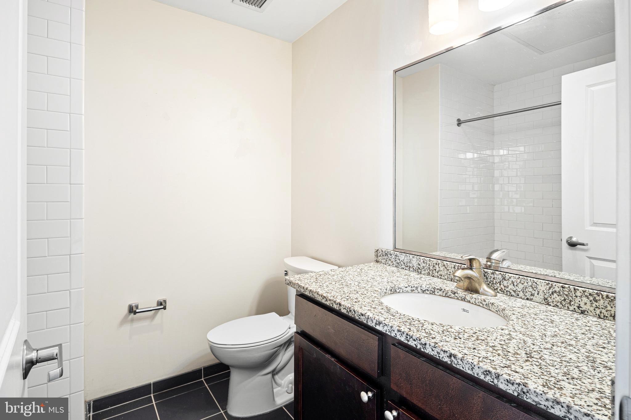 523 North Broad Street, Unit P1 Philadelphia, PA 19123 - Photo 20 of 37 a bathroom with a granite countertop sink a toilet and a mirror