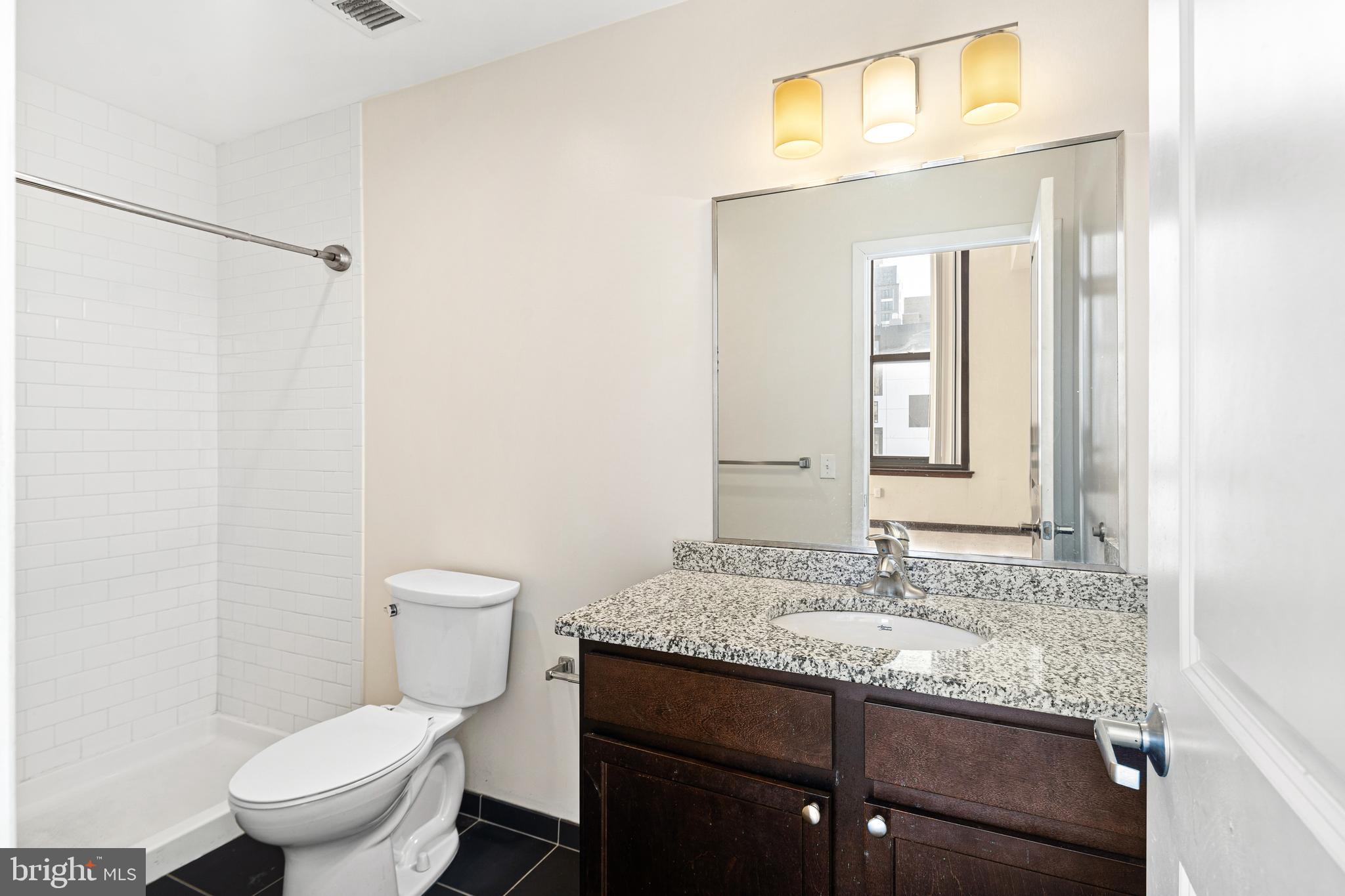 523 North Broad Street, Unit P1 Philadelphia, PA 19123 - Photo 24 of 37 a bathroom with a granite countertop sink a toilet and a mirror