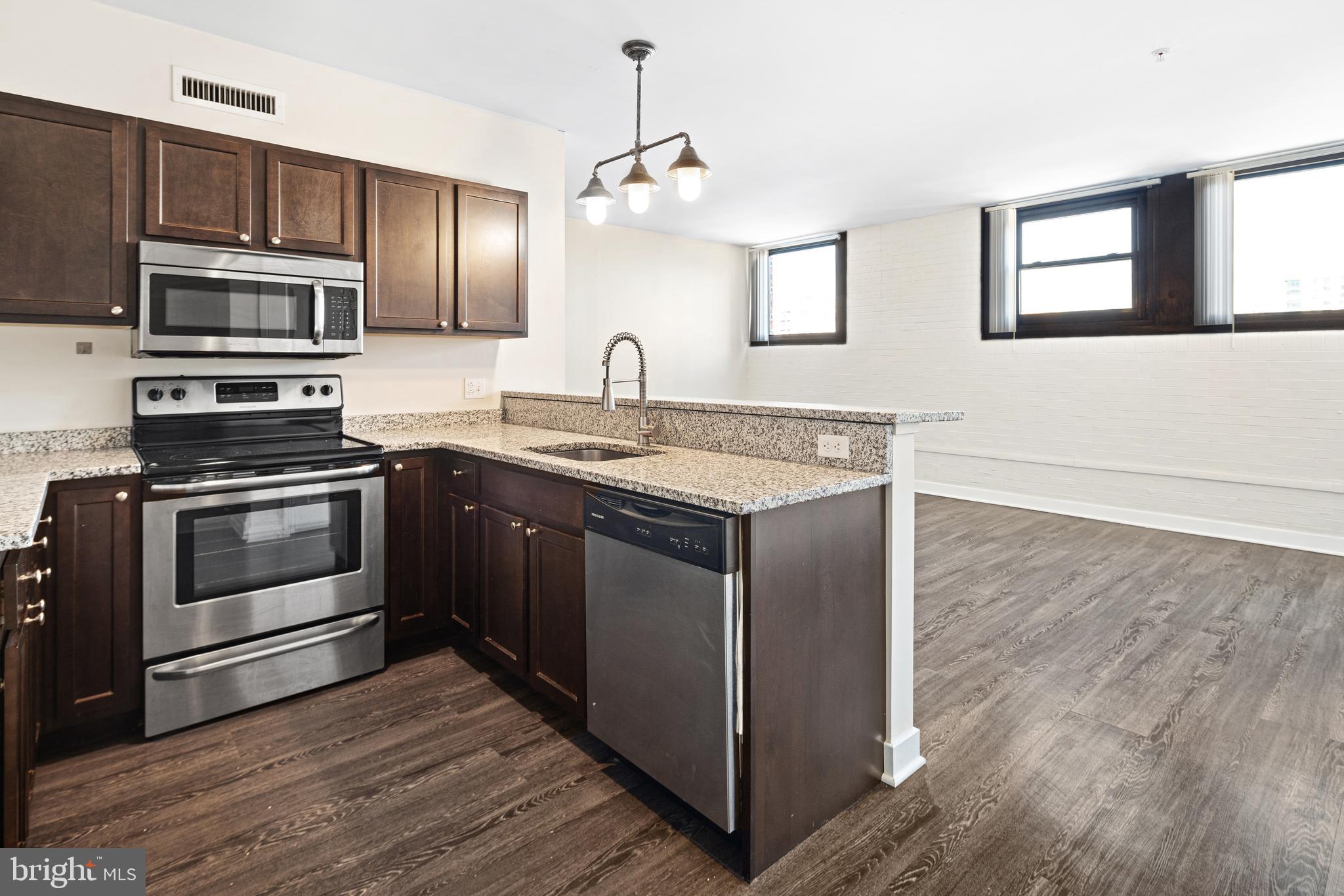 523 North Broad Street, Unit P1 Philadelphia, PA 19123 - Photo 25 of 37 a kitchen with stainless steel appliances kitchen island granite countertop a stove a sink and a microwave