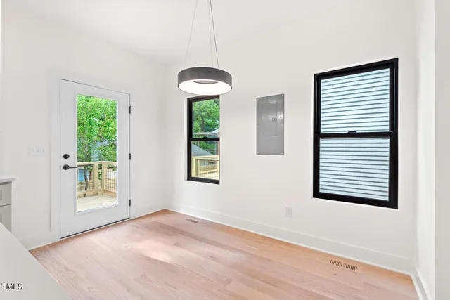a view of an empty room with a window and wooden floor