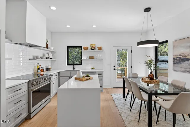 a kitchen with stainless steel appliances a dining table chairs stove and white cabinets