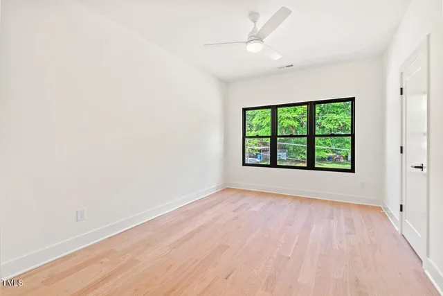 an empty room with wooden floor cabinet and windows