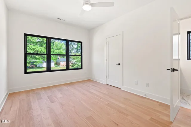 a view of an empty room with a window and wooden floor