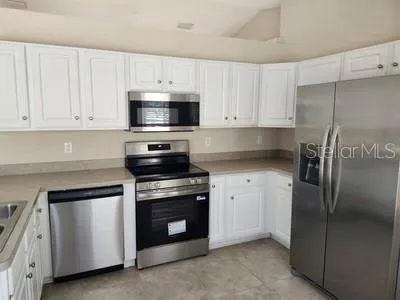 a kitchen with cabinets stainless steel appliances and a counter space