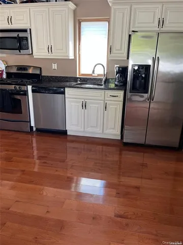 a kitchen with granite countertop a refrigerator a sink a stove and cabinets