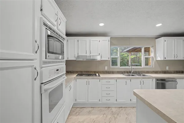 a kitchen with white cabinets and appliances