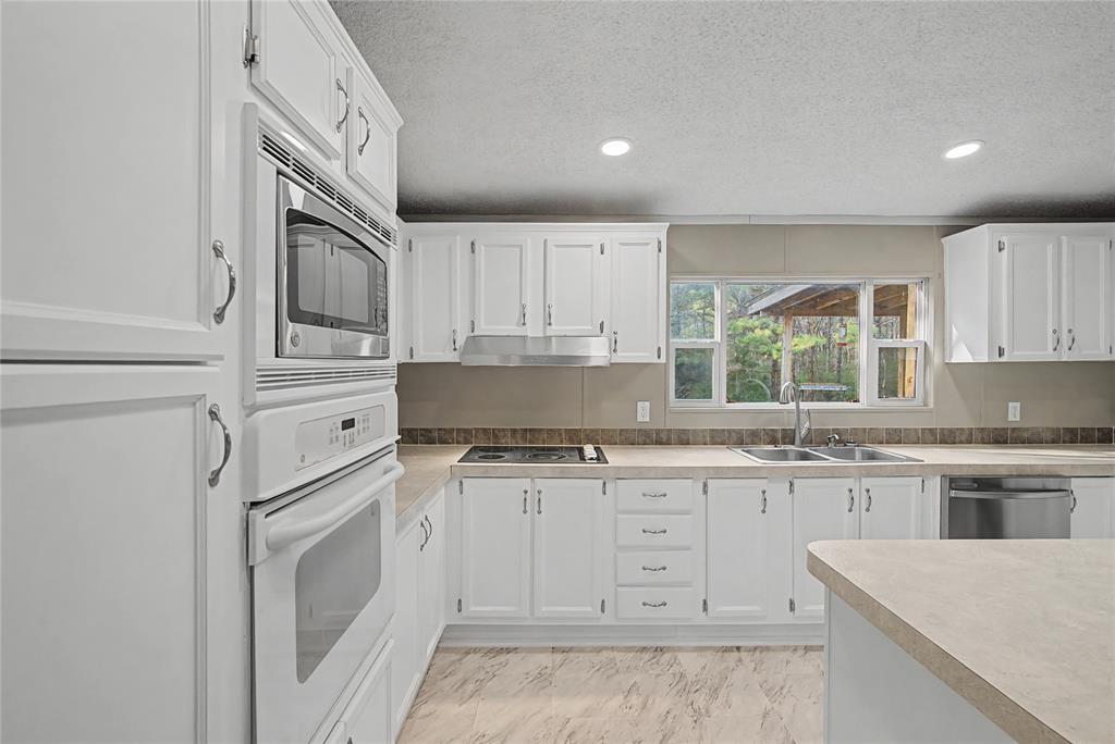 428 Cash Blackmon Road Logansport, LA 71049 - Photo 12 of 40 a kitchen with granite countertop white cabinets white stainless steel appliances with a sink and dishwasher