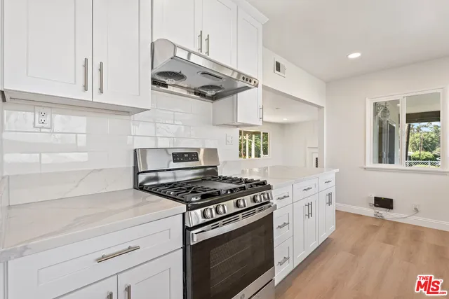a kitchen with stainless steel appliances granite countertop a sink a stove and cabinets