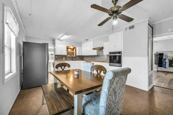 a kitchen with kitchen island stainless steel appliances a table chairs and a refrigerator