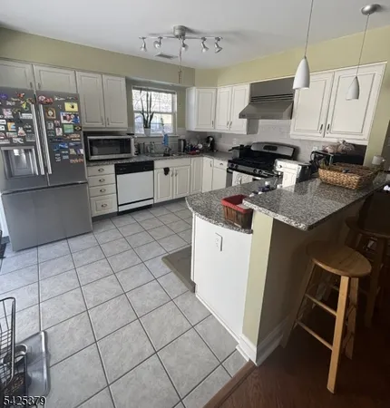 a kitchen with stainless steel appliances a stove a sink a microwave a refrigerator and cabinets