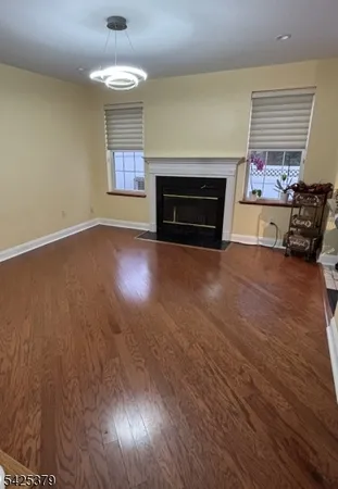 an empty room with wooden floor fireplace and windows