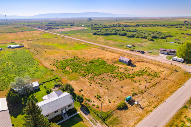 161 South 2nd Street East Paris, ID 83261 - Photo 1 of 28 Expansive property featuring a detached house with a metal roof, a distinct outbuilding, and a gravel driveway, surrounded by open fields and distant mountains