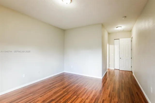 a view of an empty room with wooden floor and a window