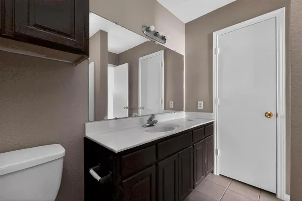 a bathroom with a granite countertop sink and a toilet