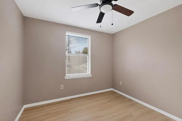 an empty room with a window and a fan