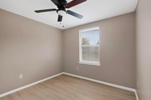 an empty room with a window and a fan