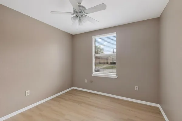an empty room with a window and a fan