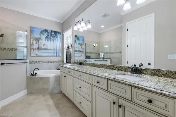 a bathroom with a granite countertop bathtub a double vanity sink a vanity and a large mirror