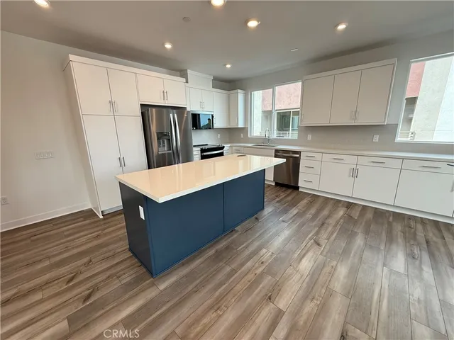 a large kitchen with wooden floors and stainless steel appliances