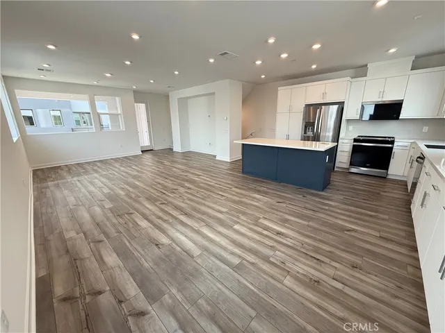 a large kitchen with stainless steel appliances granite countertop a large counter top and a wooden floors