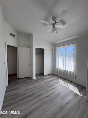 an empty room with wooden floor fan and windows