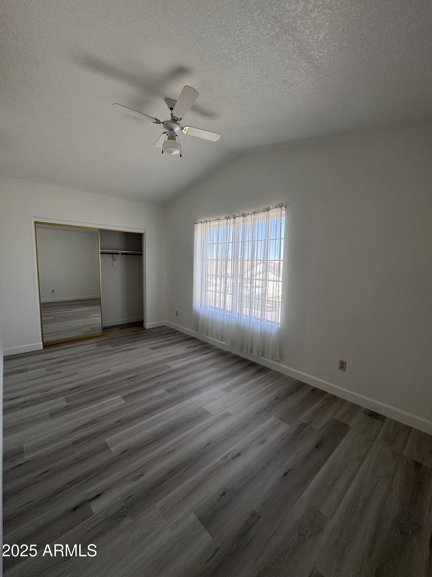 8631 West Monte Vista Road Phoenix, AZ 85037 - Photo 25 of 26 an empty room with wooden floor and windows