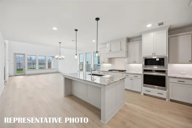 a large white kitchen with a refrigerator a sink dishwasher a oven and a dining table with wooden floor