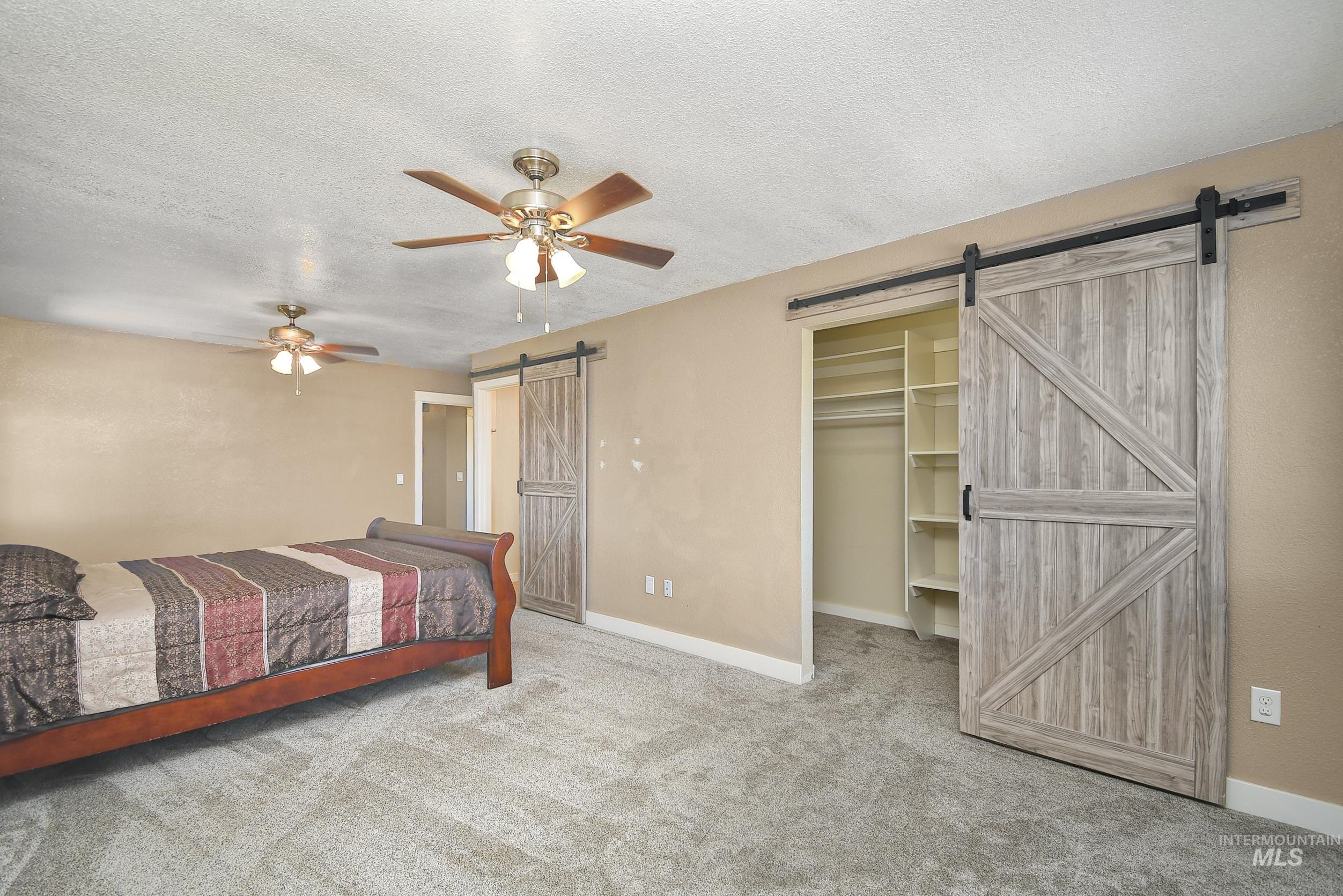 1108 East Ustick Road Caldwell, ID 83607 - Photo 23 of 30 Room featuring a wood-finish barn door, built-in closet shelving, and a ceiling fan