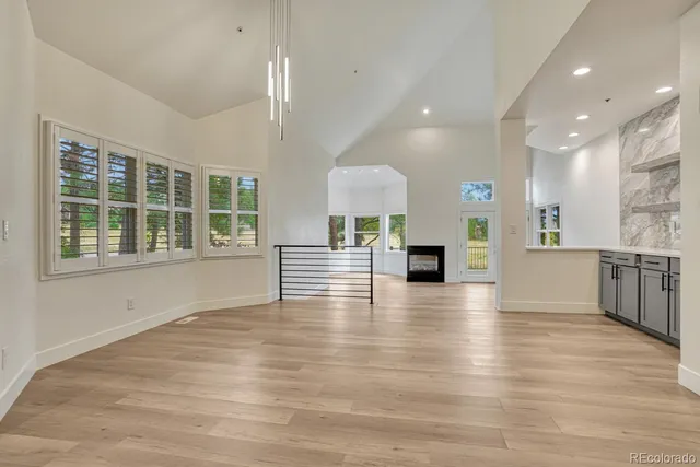 an empty room with wooden floor and a kitchen