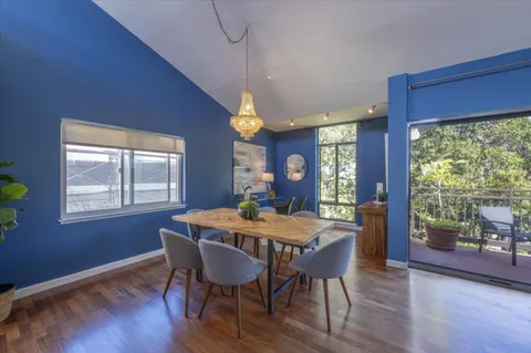 a dining room with wooden floor a chandelier a wooden table and chairs