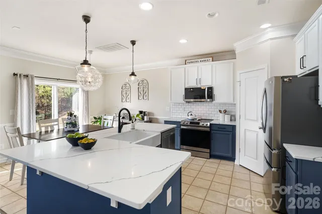 a kitchen with stainless steel appliances granite countertop a dining table chairs a microwave and a refrigerator