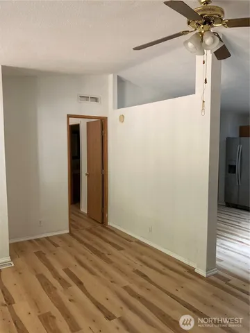 a view of an empty room with wooden floor and a bathroom