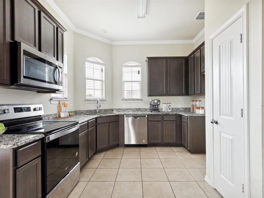 a large kitchen with granite countertop a stove top oven a sink dishwasher and a refrigerator with wooden cabinets