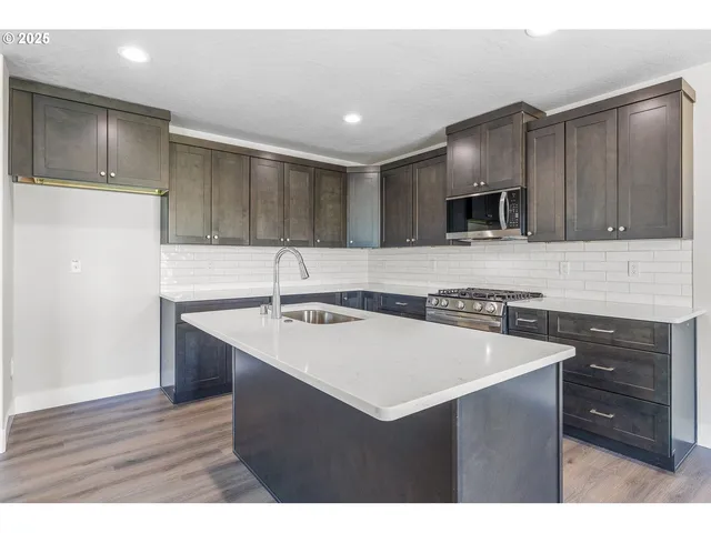 a kitchen with kitchen island a sink stainless steel appliances and cabinets