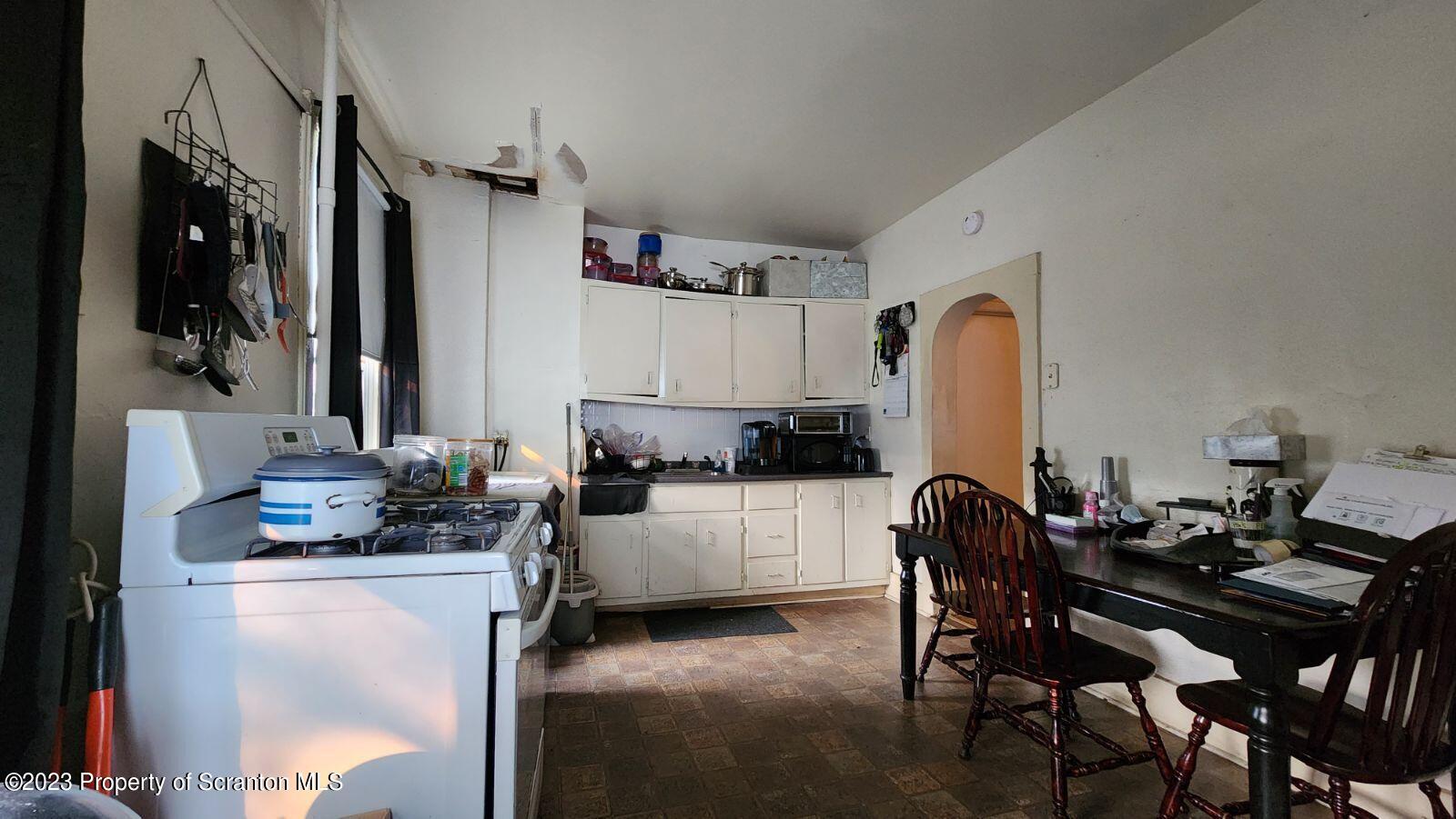 1613 Olive Street Scranton, PA 18510 - Photo 9 of 22 a kitchen with a table chairs refrigerator and cabinets