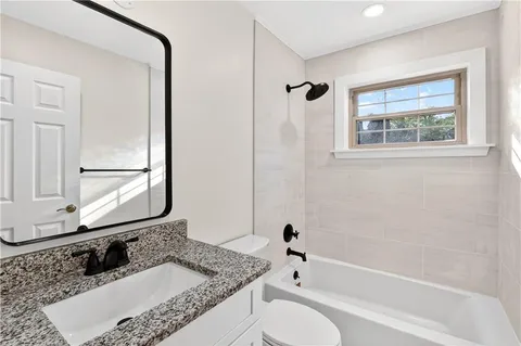 a bathroom with a granite countertop tub sink and mirror