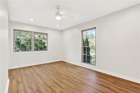 an empty room with wooden floor and windows