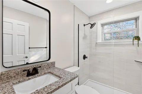 a bathroom with a granite countertop sink mirror vanity and toilet