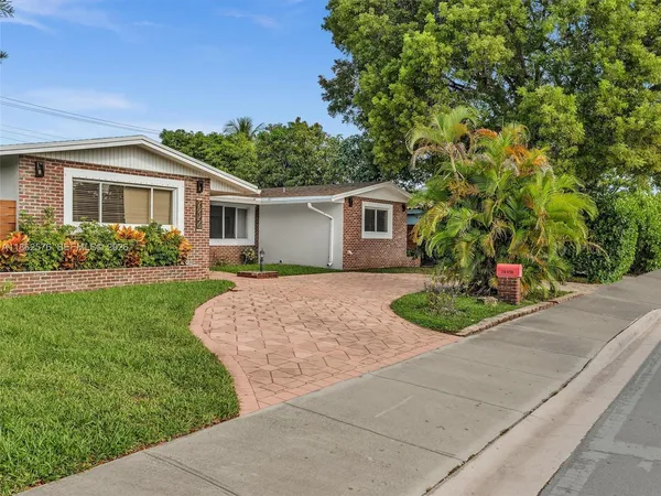 a front view of a house with a yard and potted plants